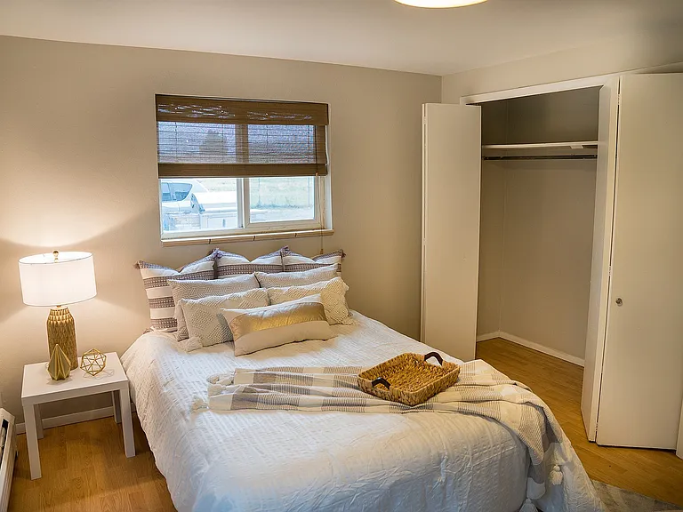 Cozy bedroom with elegant decor, featuring a plush bed, modern lamp, and an open closet, creating a warm and inviting ambiance.