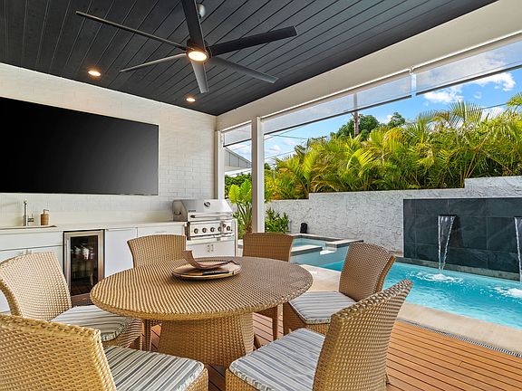 85" Flatscreen TV mounted, outdoor kitchen with sink, built in grill, beverage fridge, & commercial stand alone Icemaker