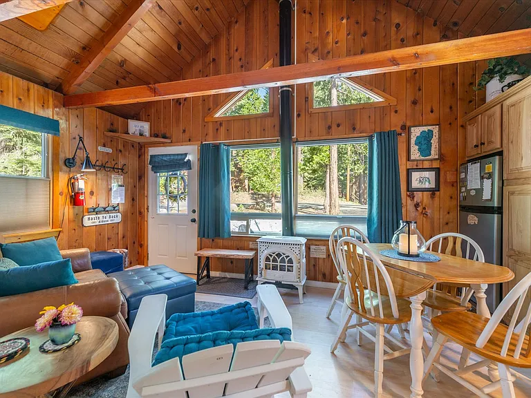 Main living area, dining, kitchen with vaulted ceilings, knotty pine wood accents and gas stove.