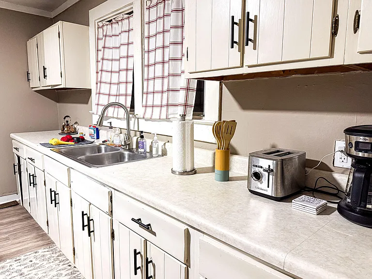 Functional kitchen counter and double-basin sink with ample cabinetry, plus convenient small appliances and a window over the