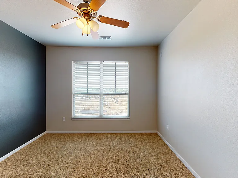 Spacious apartment bedroom with plush carpet flooring.