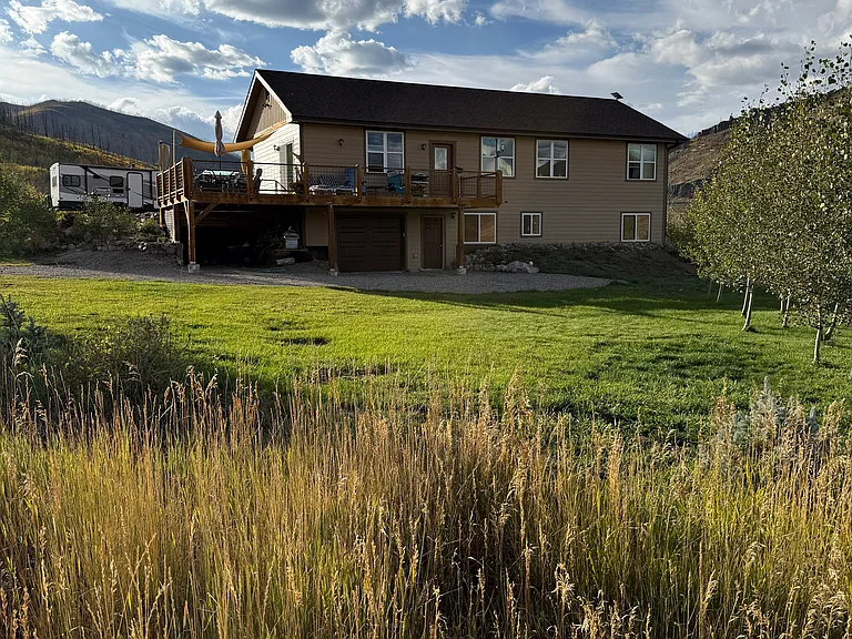 showing the below apartment entrance and garage door. Beautiful green lawn. Owners take care of gardens and lawn care.
