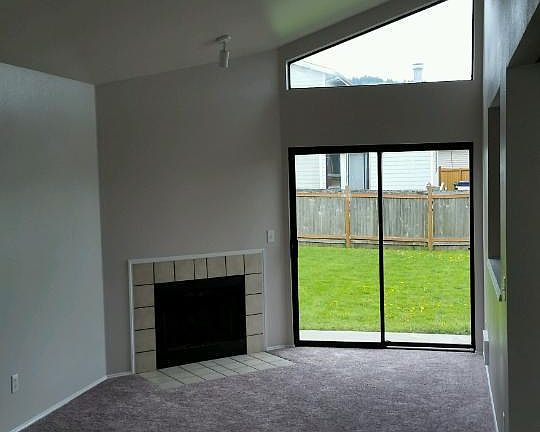 Living Room with cozy wood-burning fireplace, sliding patio door to spacious outside back yard. Office/Den off to right.