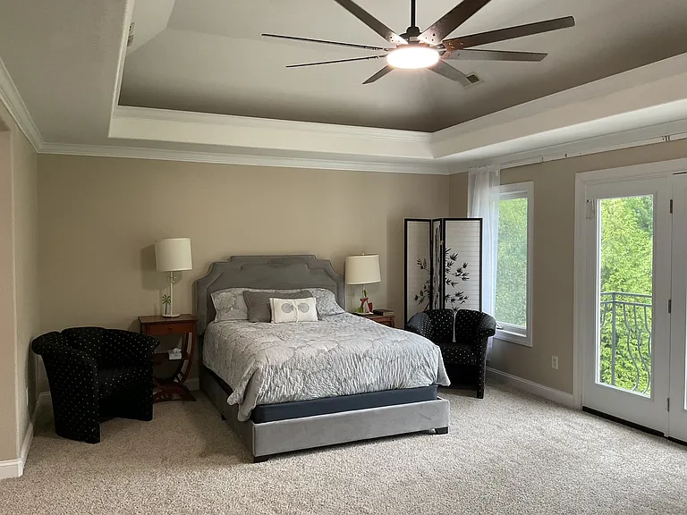 Full view of primary with recessed ceiling and large ceiling fan.