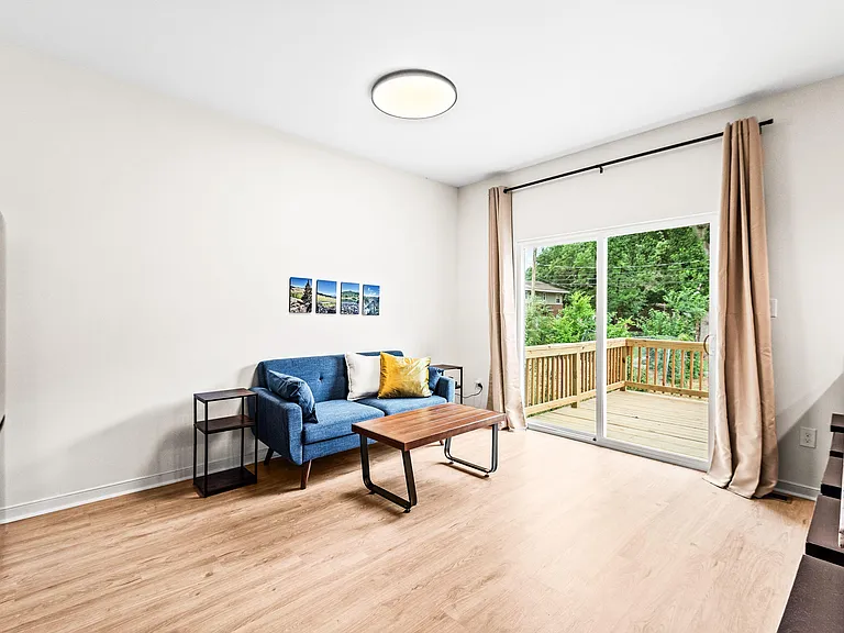 Open living area with seating, coffee table, and large sliding doors leading to a private deck with wooded views.