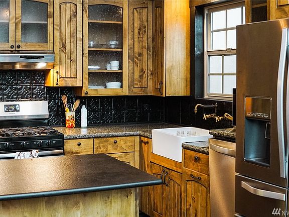 Kitchen with custom cabinetry, stainless steel appliances, black satin island, and granite countertops.