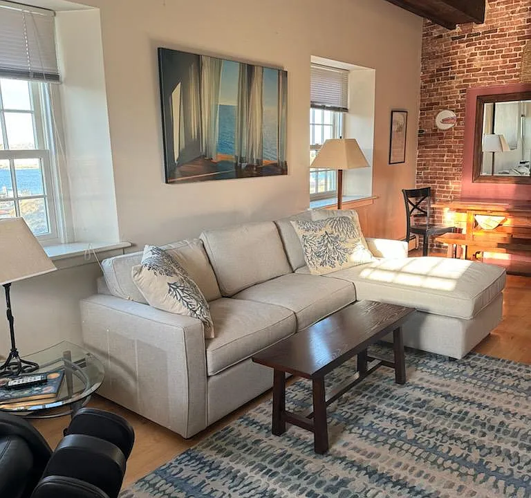 New Room and Board sectional complete this living/dining area with beamed ceilings. Windows overlook the harbor.