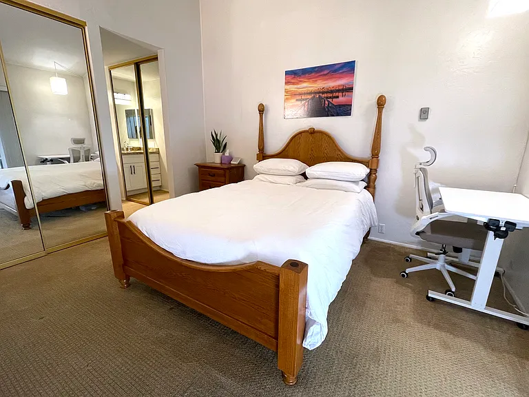 Secondary bedroom with queen bed, convertible standing desk, and double closets