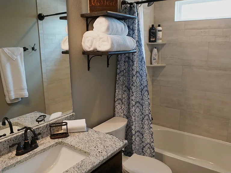 The master bathroom features a shower/tub combo, granite-topped vanity, bronze fixtures, and built-in storage for towels and essentials all attached to a huge walk-in closet.