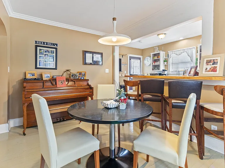 Dining room at Hunsucker's Place features a piano and a view into the kitchen. Located within walking distance of Cone Health Hospital and Downtown Greensboro, this space is perfect for enjoying meals and music in a cozy, central location.