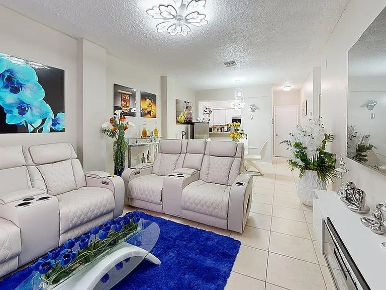 Elegant living area with plush cream recliners, vibrant blue accents, and modern decor, perfect for relaxation and entertaining.