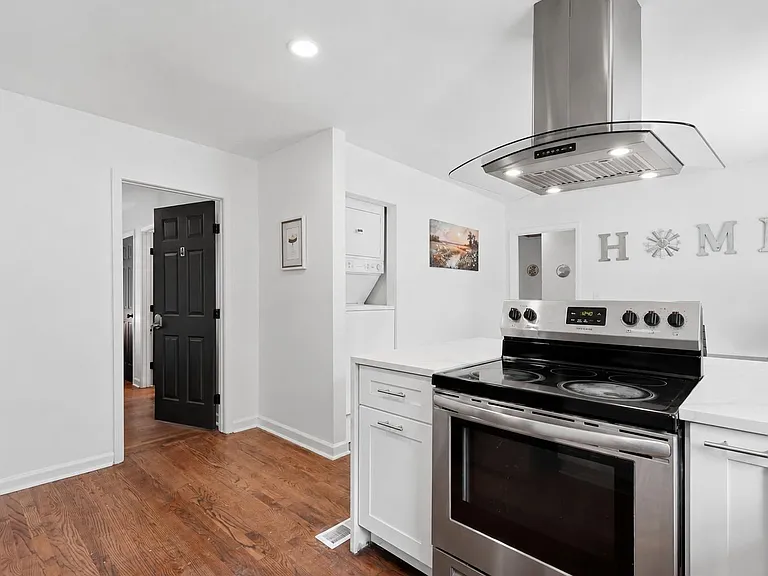 Open kitchen with stainless electric range, vent hood, and generous counter space, plus nearby in-unit laundry.