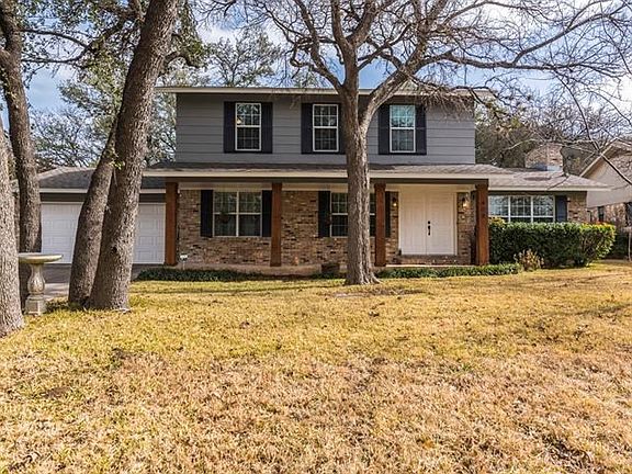Front of home has mature trees and a beautiful covered porch.