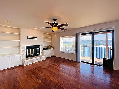 Living rm w/ fireplace looking out over lake.