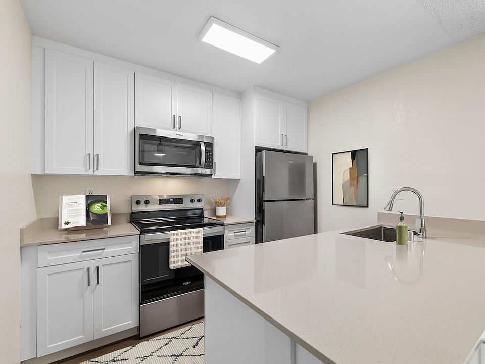Renovated Package I kitchen with stainless steel appliances, white cabinetry, beige quartz countertops, and hard surface flooring