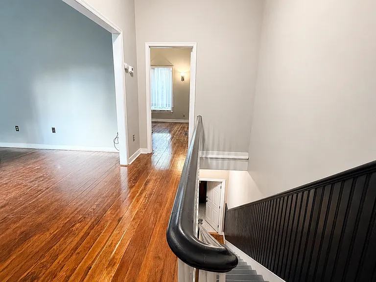 Private entrance with a bright stairwell, high ceilings, classic railing detail, and hardwood flooring.