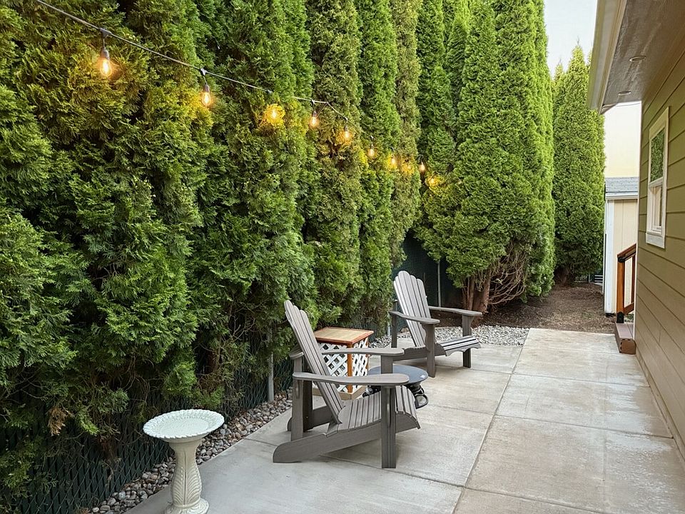 Secluded with tall arborvitaes. Seating, warm lights, fire pit or grill a burger, steak or shish kabobs on the kettle style mini grill.