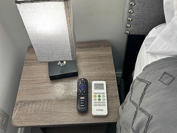 Room includes nightstand, lamp, AC and TV remotes.