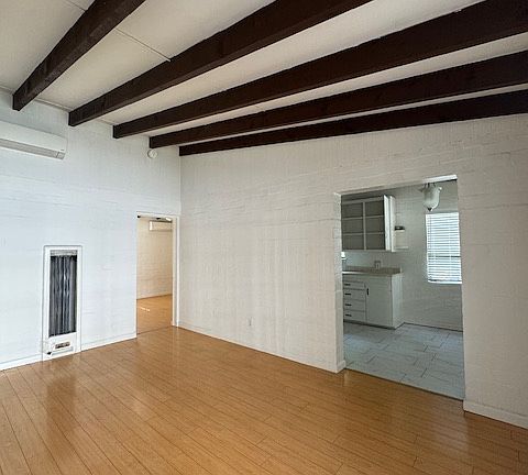 BEAMED, VAULTED CEILING IN LIVING ROOM (LOOKING INTO BEDROOM IN BACK AND KITCHEN/DINING ON RIGHT)