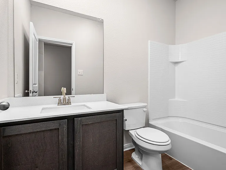 The secondary bedroom has a sprawling vanity and shower-tub combo.