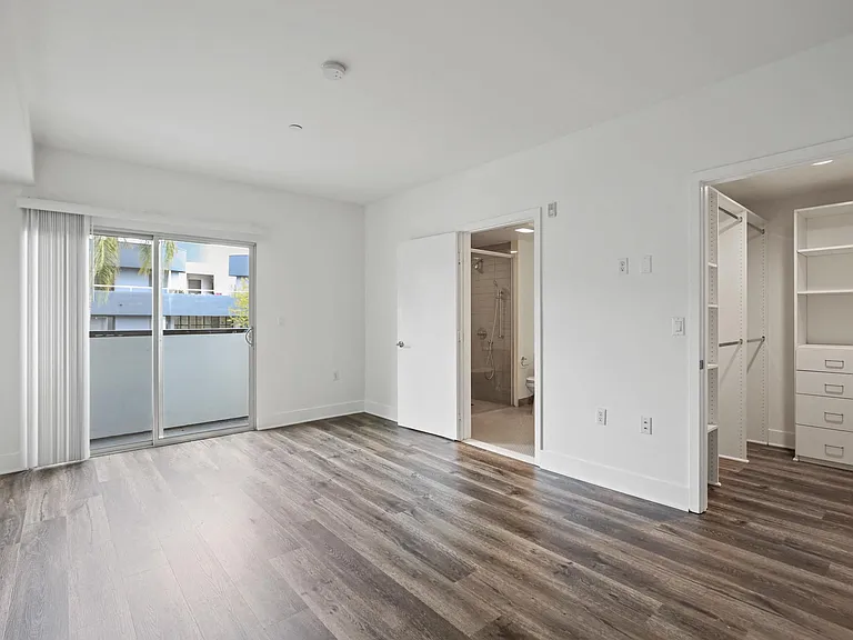 Bedroom with Walk-In Closet with Built-In Shelving, Bathroom, and Balcony