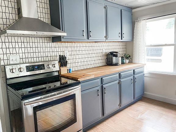 Refinished kitchen sink, stainless steel appliances, and custom tile backsplash
