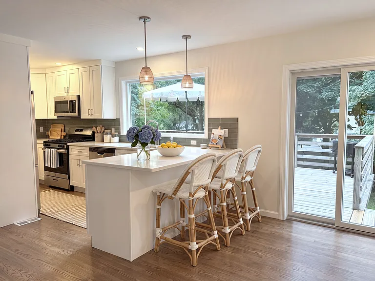 Bright kitchen with picture window, gas stove, quartz countertop, pantry, and large island (virtually staged)