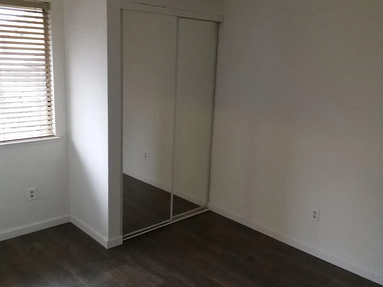 Second Bedroom with ceiling fan and mirror closet door and Pergo Flooring.