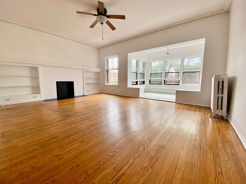Spacious Living Room with decorative fireplace and built-in shelving opens to sun parlor with lots of natural light