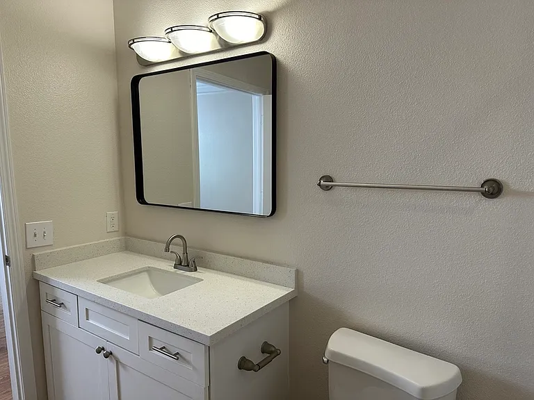 Modern bathroom with sleek white vanity, spacious quartz countertop, and elegant mirror under stylish lighting. Modern bathroom with sleek white vanity, spacious quartz countertop, and elegant mirror under stylish lighting.