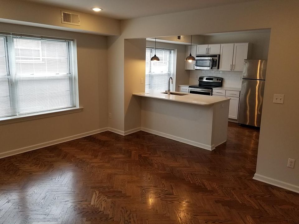 Living room with herringbone hardwood floors, open to the ki