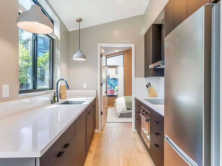 Freestanding home kitchen with stainless steel appliances, white quartz countertops, black cabinetry, and hard surface flooring