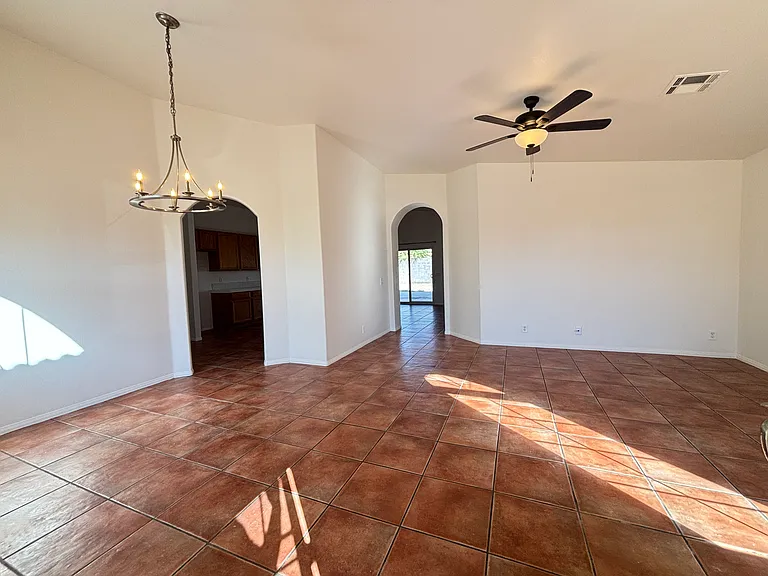 Spacious living and dining area with ceiling fan, high ceilings, and plenty of natural light.