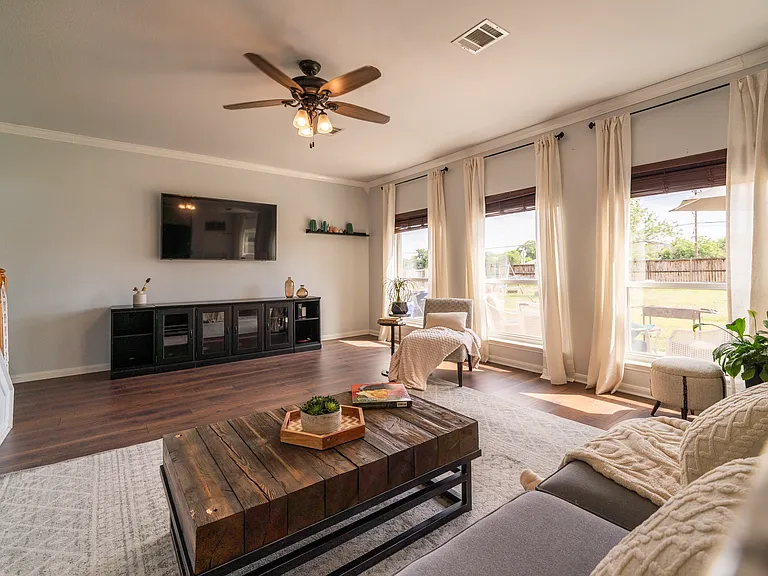 Sun-Drenched Living Space: Relax in a bright, airy living room framed by tall windows that let in an abundance of natural light. Cozy up in a beautifully styled layout that offers plenty of room for comfortable seating and media setups.