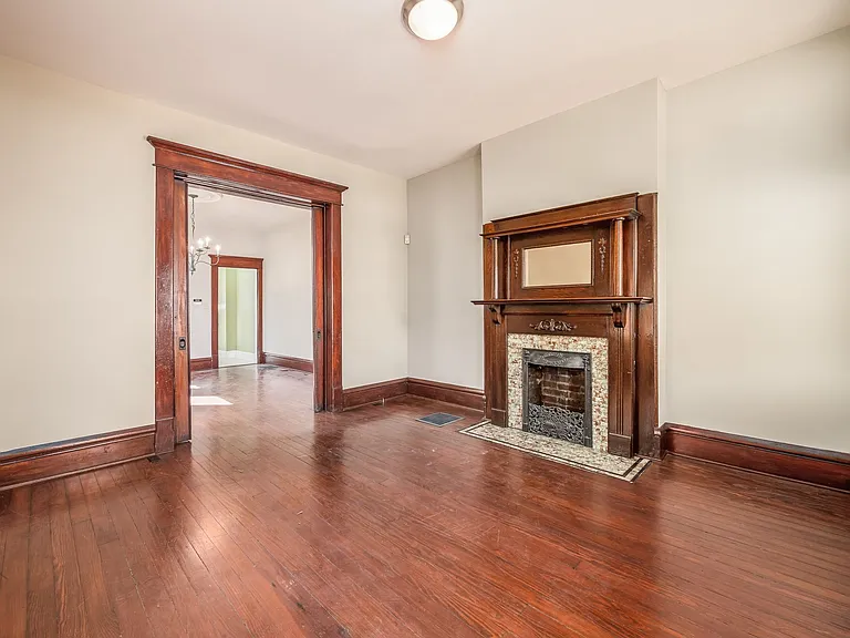 Living room with working pocket doors and decorative original fireplace.