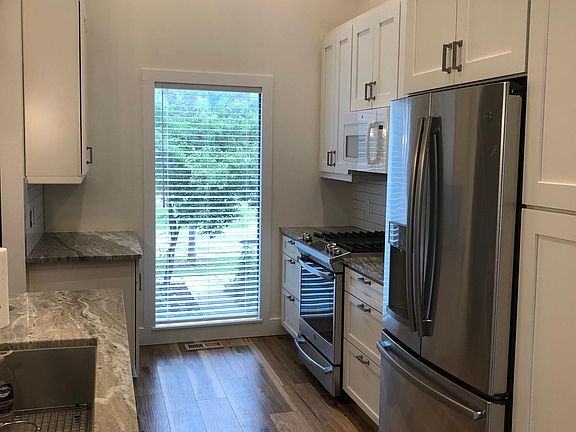 Open galley kitchen design with bright window overlooking entry.