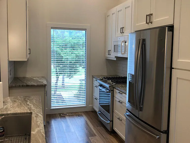 Open galley kitchen design with bright window overlooking entry.