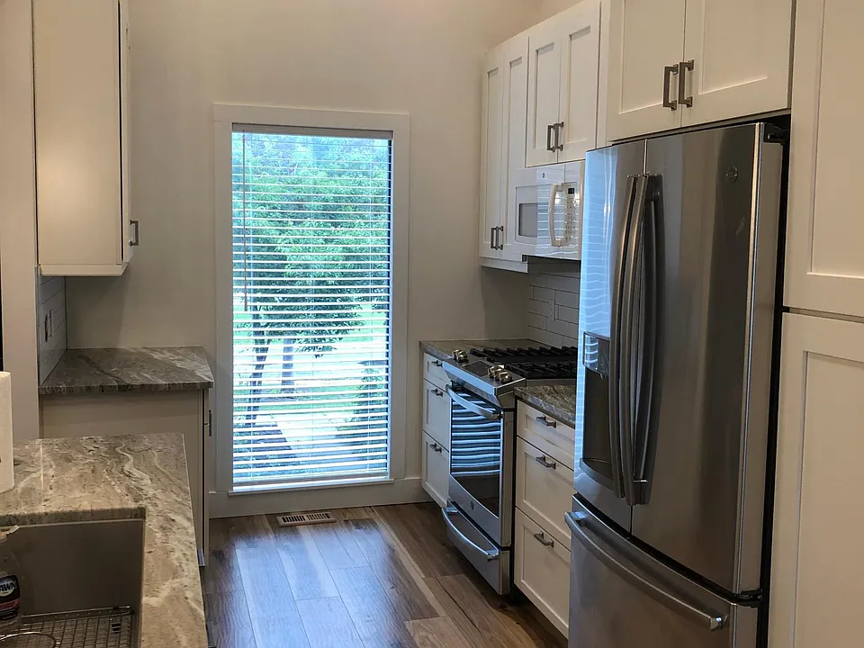 Open galley kitchen design with bright window overlooking entry.