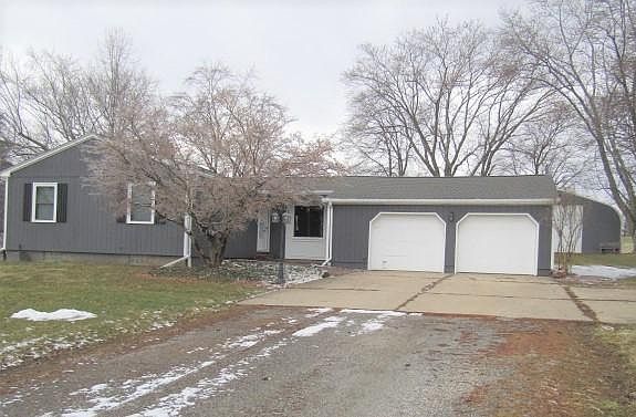 Ranch-style home is dark gray with white trim. Well water and septic.