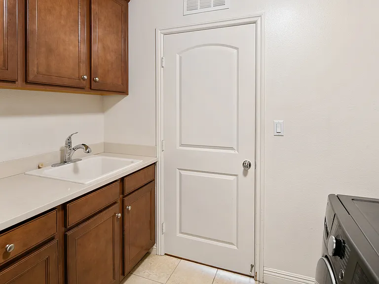 Separate Laundry Room with lots of cabinet and sink next to the 3 Car Garage.