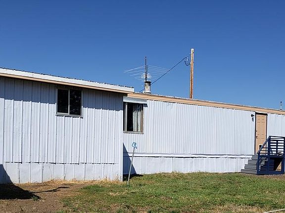 This outside view shows the roughed in, covered and enclosed back porch addition. Also shows steps leading into the hallway section of home, via the hall door.