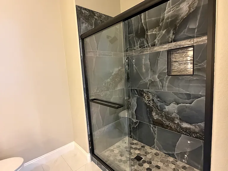 Loft bathroom shower featuring a glass enclosure, large-format tile surround