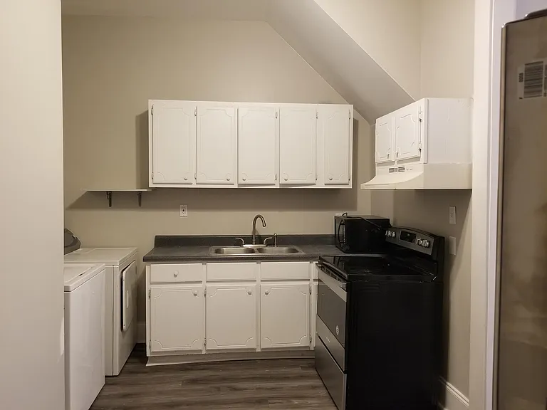 Black refrigerator and electric flat-top stove. Current tenants are selling a washer and dryer, and leaving a coffee table which can be hauled away upon request.