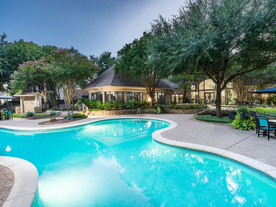 A refreshing retreat awaits at the resort-style pool, surrounded by mature trees, stonework, and peaceful gathering spaces.