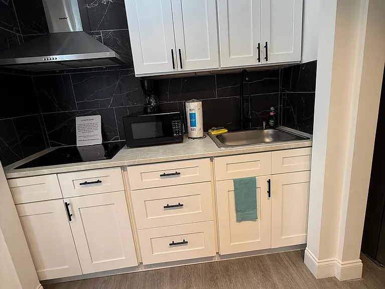 Fully equipped kitchen with stove, cabinets, range hood, microwave, and essentials.