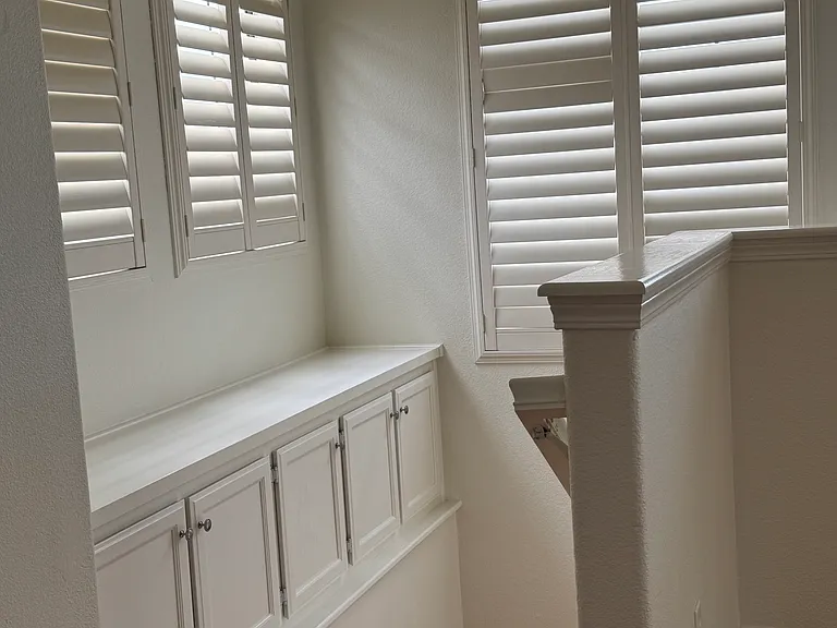 Stairwell with lots of windows and shelf with cabinets