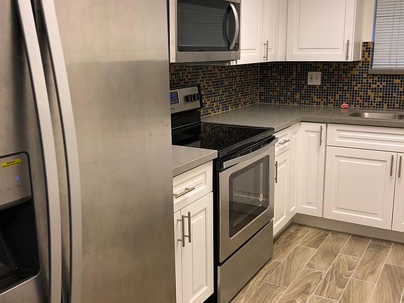 New stainless steel flat-top electric range and microwave oven and stainless steel refrigerator in the remodeled kitchen.
