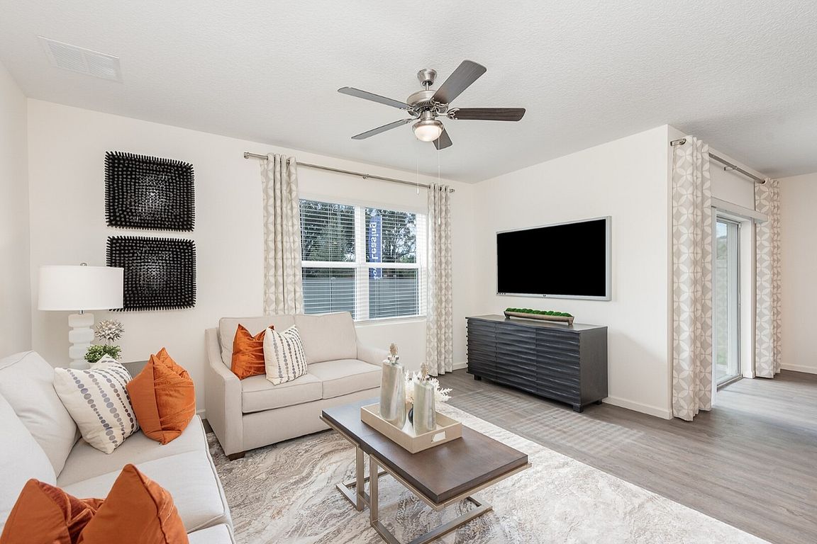 Bright and modern living room featuring sleek decor, plush seating with vibrant pillows, and a large wall-mounted television, perfect for relaxation and entertaining.