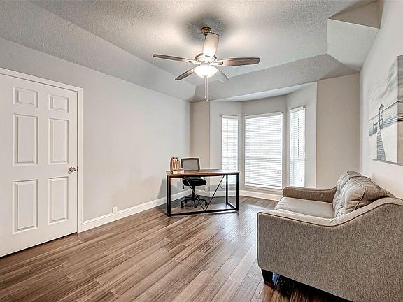 Secondary bedroom is used as a study and has natural light beaming in, with a stylish ceiling fan.