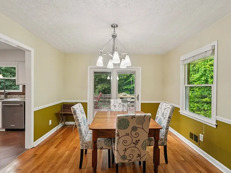 Framed by windows and glowing with warmth, this dining area offers a delightful place to gather, dine, and enjoy the quiet charm of home.